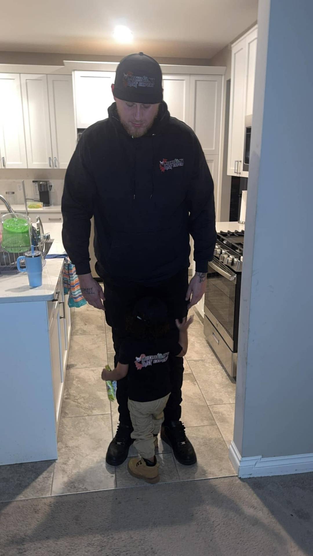 Sam at home with his young son, both wearing Michigan's Bat Expert gear